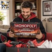 Man smiling while holding Arizona Cardinals Monopoly collector edition board game.