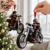 Two Easy Rider movie-themed biker Christmas ornaments hanging from fingers with a holiday tree background.