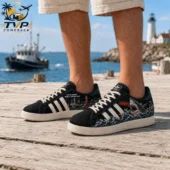 Person wearing Jaws-themed black sneakers with shark and boat illustrations on a wooden dock.