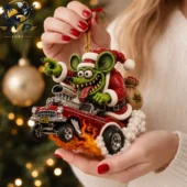 A detailed Rat Fink style Christmas tree ornament showing a green monster in a Santa suit driving a red hot rod.