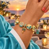 Kenny Chesney No Shoes No Shirt No Problems Gold Charm Bracelet Set 2026 2 Gold bracelet with beach-themed charms on a wrist at sunset